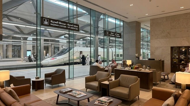 Luxury VIP lounge at Madinah Haramain High Speed Railway Station overlooking a high-speed train platform in Saudi Arabia.